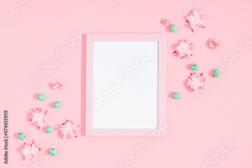 Easter decor, composition. Empty photo frame, flowers, easter eggs on pastel pink background. Flat lay, top view, copy space © prime1001