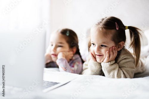 Two girls sisters watching on laptop. Technology and home concept.
