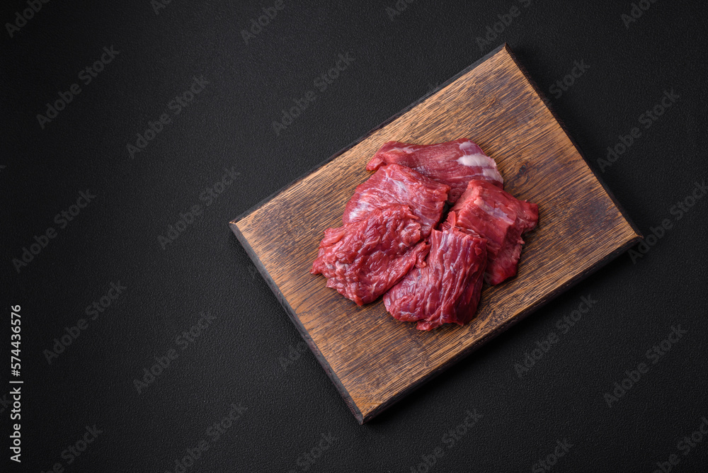 Raw beef cut into several pieces on a wooden cutting board