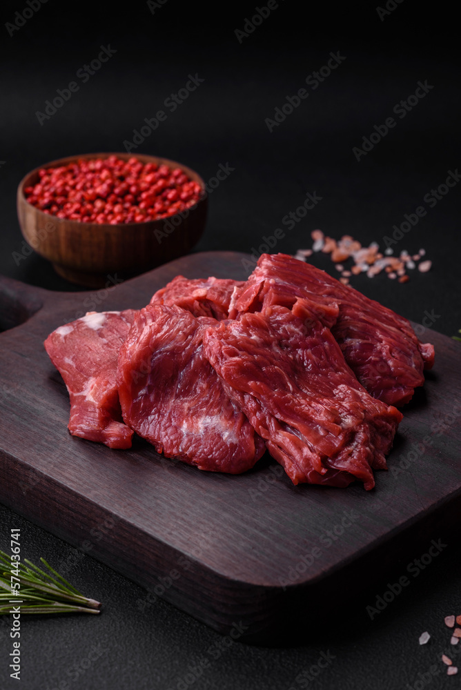 Raw beef cut into several pieces on a wooden cutting board