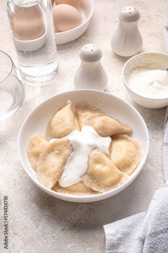 Fresh boiled dumplings in a light plate on a light background. Pattern, background. Homemade craft production, national traditions, Ukrainian cuisine