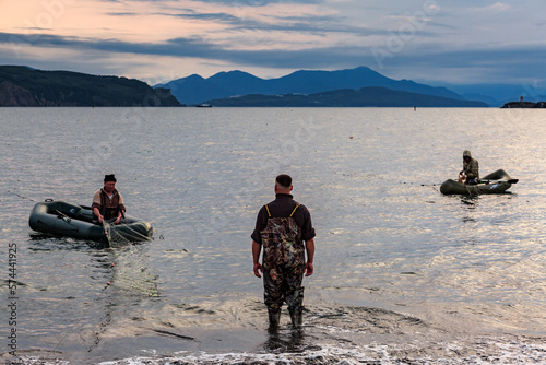 Pacific Ocean, sunset, fishermen on boats are catching fish with nets. Kamchatka.