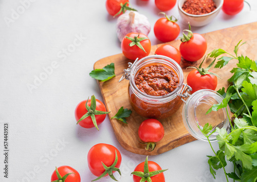 Salsa or adjika sauce is a traditional Mexican or Caucasus sauce with tomatoes and hot peppers on a light background with fresh herbs.