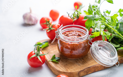 Salsa sauce is a traditional Mexican sauce with tomatoes and hot peppers on a light background with fresh herbs close up.