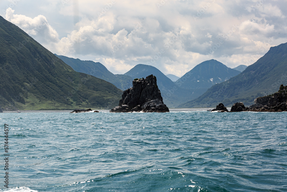 Rocks and mountains of various shapes in the Pacific Ocean, clear sunny day, blue water, Kamchatka.
