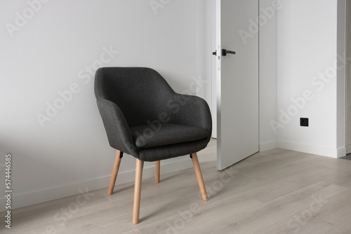 Gray chair against an empty white wall, with a concealed door