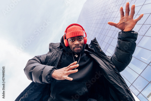 Upbeat Vibes - Low-Angle Street Fashion Portrait of a Super Cool African American Man Dancing to Hip-Hop Beats Groove photo