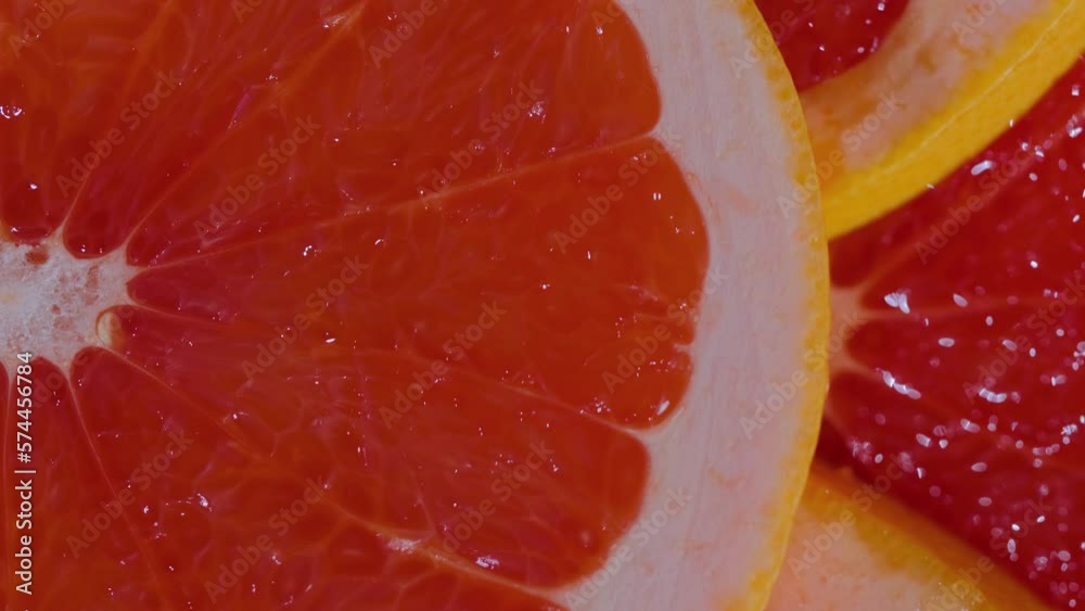 Colorful fresh red citrus fruit slices of grapefruit on rotating surface - close up, top view, macro. Summer, tropical, natural, exotic and healthy food concept Colorful fresh red citrus fruit slices of grapefruit on rotating surface - close up, top view, macro. Summer, tropical, natural, exotic and healthy food concept