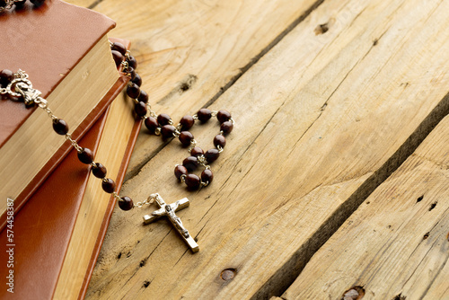 Image of close up of two holy bibles with rosary and copy space on wooden background