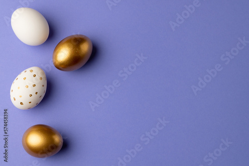 Image of multi coloured easter eggs and copy space on purple background
