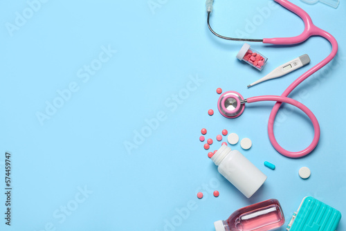 Foto Stethoscope with thermometer and medications on blue background