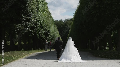 Bruhl, Cologne, Germany - 25 Jul, 2022: Wedding couple broom and bride walk in gardens of Augustusburg castle in Bruhl near Cologne, Germany, slow motion photo