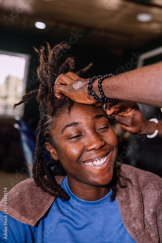 A young queer masculine woman retwisting her dreadlocks