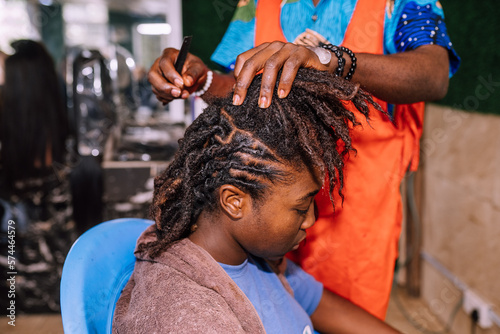 Valokuva A young queer masculine woman retwisting her dreadlocks