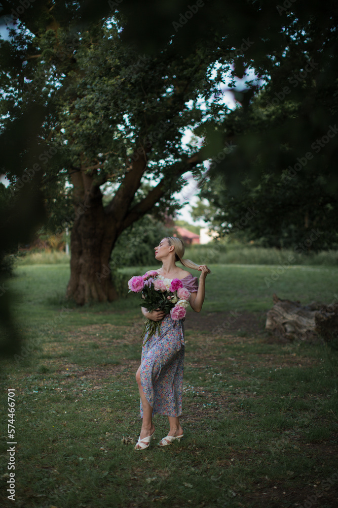 Fototapeta premium beautiful blonde woman with beautiful bouquet of peonies.
