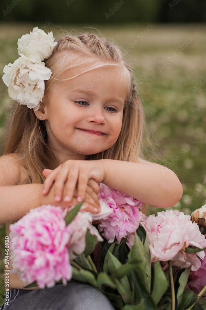 Fototapeta premium Beautiful little girl with big peonies bouquet. Spring blossom and carefree childhood concept.