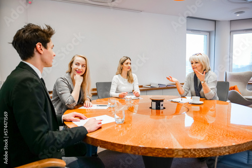 People talking and laughing during a conference at a round table at work