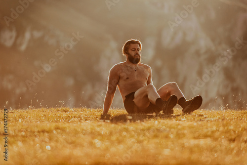 A man doing abs exercises on top of a mountain © Minet