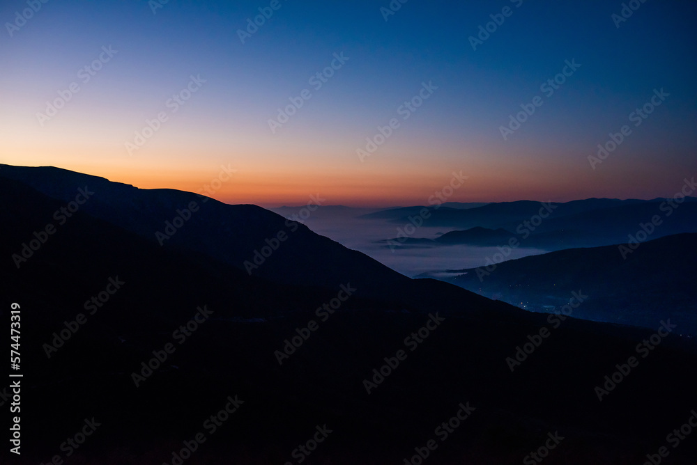 Fototapeta premium Mountain range with visible silhouettes through the morning colorful fog