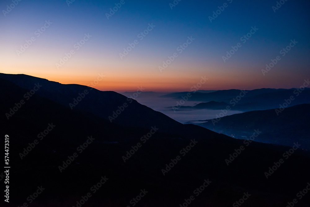 Mountain range with visible silhouettes through the morning colorful fog