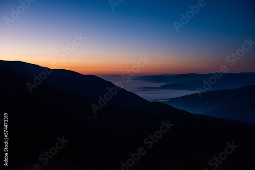 Mountain range with visible silhouettes through the morning colorful fog © Minet