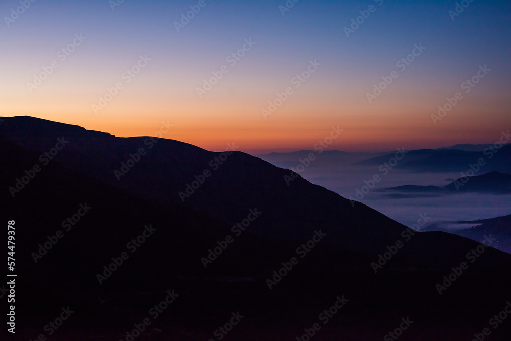 Mountain range with visible silhouettes through the morning colorful fog