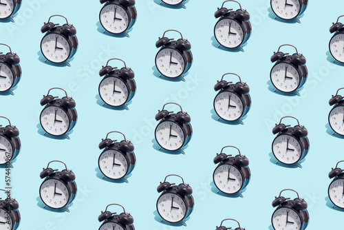 Seamless pattern of black retro alarm clocks  show 3 o'clock. Changing clock from summer time to winter time. Shifting the clock hands back in autumn.