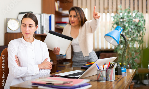 Unhappy woman chief screaming to young female manager during working in office