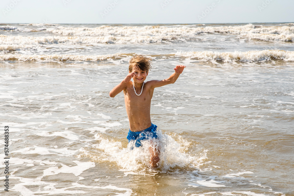 Youth Child Preteen Boy Running Into the Waves and Ocean Water at the Sunny Beach Youth Child Preteen Boy Running Into the Waves and Ocean Water at the Sunny Beach