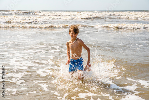 Youth Child Preteen Boy Running Into the Waves and Ocean Water at the Sunny Beach