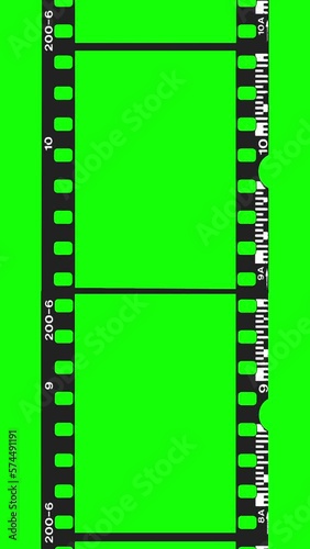 An empty 35mm black film strip moving in front of a green screen. Vertical Video photo
