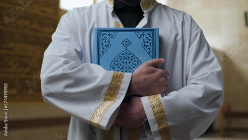 Muslim mosque imam hugs Quran tight to his chest photo