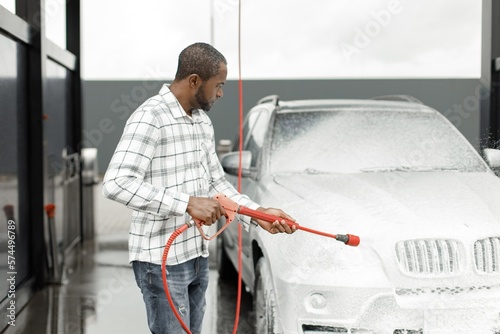 Middle aged black man cleaning his car outside in the car wash