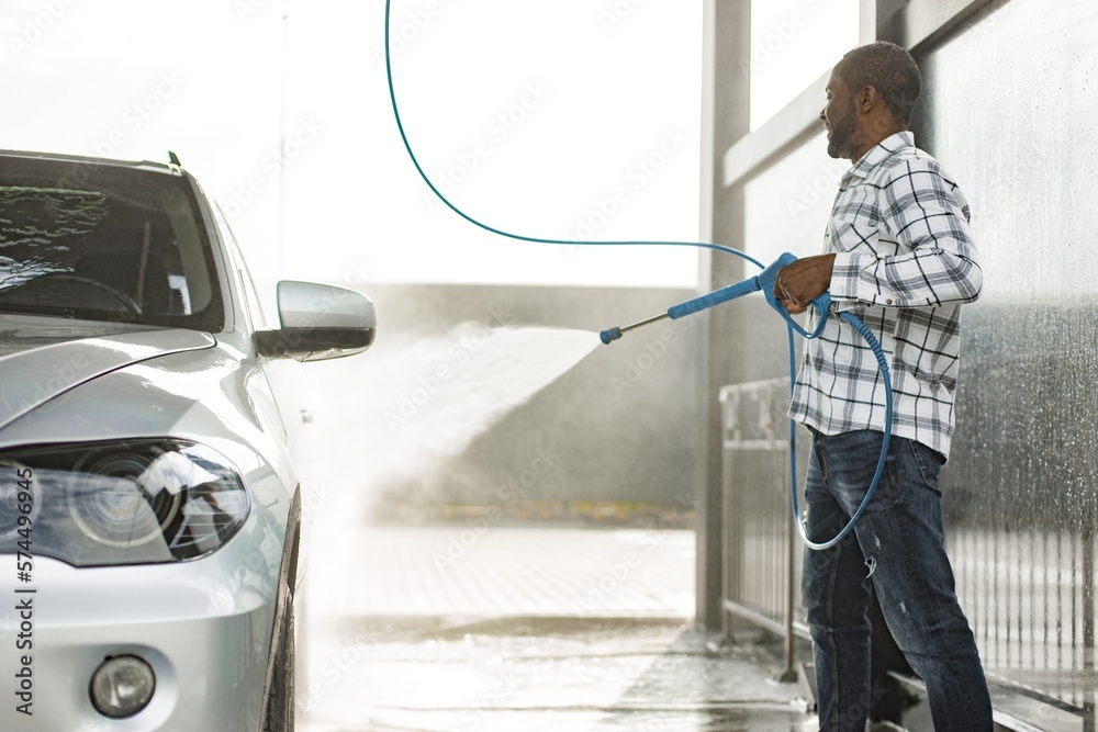 Middle aged black man cleaning his car outside in the car wash Middle aged black man cleaning his car outside in the car wash