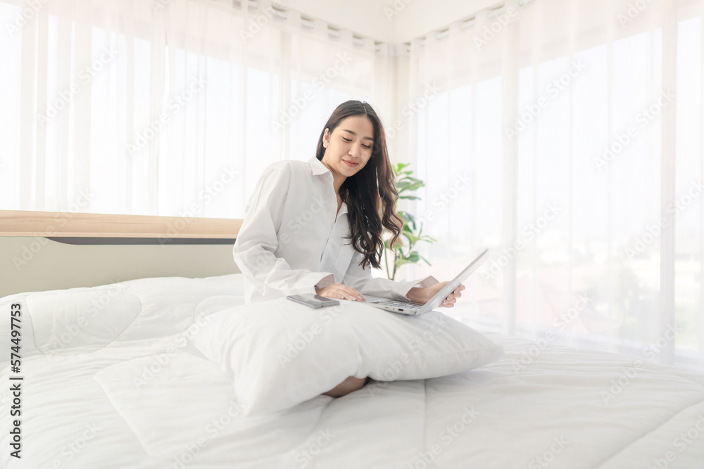 young asian woman using laptop when sitting on a bed. Smart living with ...