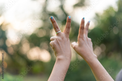 Woman hand showing number two gesture sign at sunset. © Bluesky60
