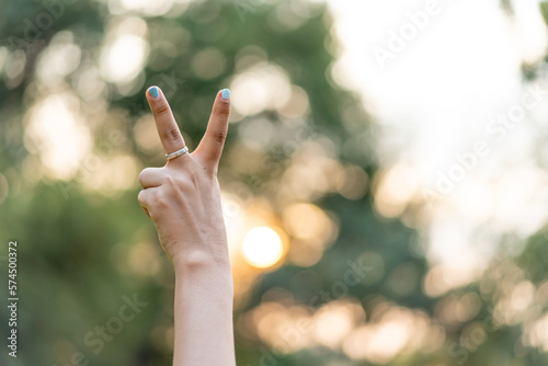 Woman hand showing number two gesture sign at sunset. © Bluesky60