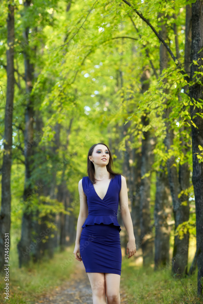 Female in blue dress walking along autumn linden tree alley. Female in blue dress walking along autumn linden tree alley.