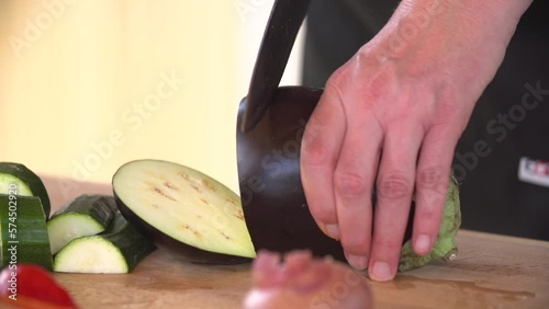 Hands Cut chopping A Fresh Eggplan On Wooden Board While Cooking photo