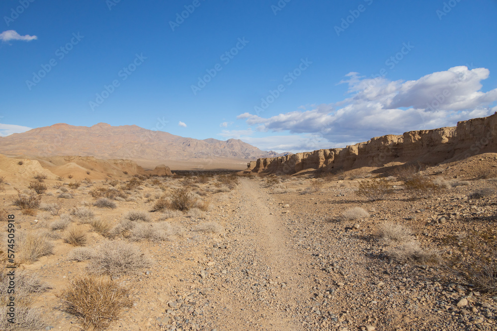 Desert with mountain background and blue sky with white clouds