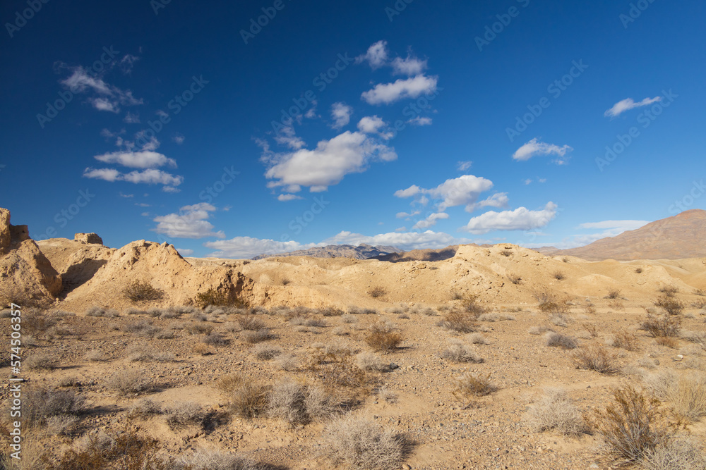 Desert with mountain background and blue sky with white clouds