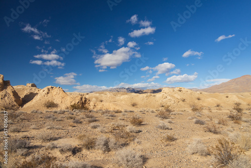 Desert with mountain background and blue sky with white clouds © Martina