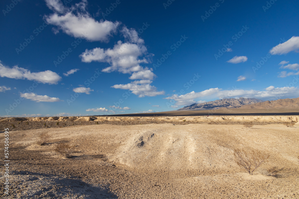 Desert with mountain background and blue sky with white clouds