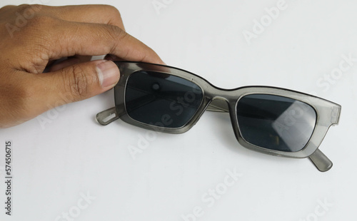 male hand holding elegant sunglasses on white background