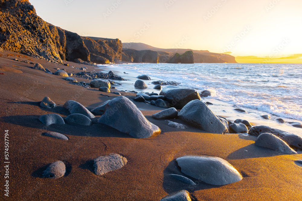 Scenic beach with black sand by low tide at sunset, Sharp mountain volcanic cliffs on Atlantic ocean coastline, Famous touristic place in Iceland - obrazy, fototapety, plakaty 