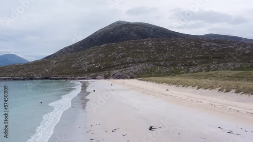 Dynamic drone shot of Luskentyre Beach on a sunny summer's day, with people visible walking along the sand. Shot on the Isle of Harris, part of the Outer Hebrides of Scotland. photo