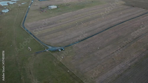 Tilting drone shot of running sheep being herded by a crofter on a quad on Berneray beach, with the machair (grass plains) in the background. Filmed on Berneray in the Outer Hebrides of Scotland. photo