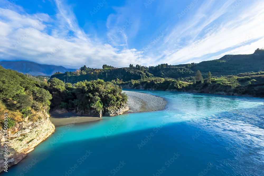 The crystal clear clean turquoise water of the Rakaia river flowing through the forest enclosed valley