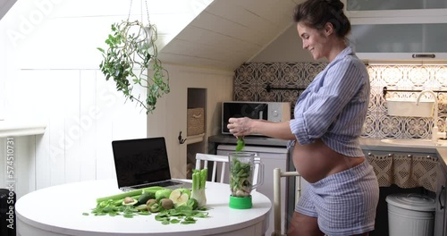 Pregnant woman doing healthy green smoothie at home.