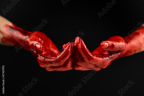 Women's hands in blood on a black background.